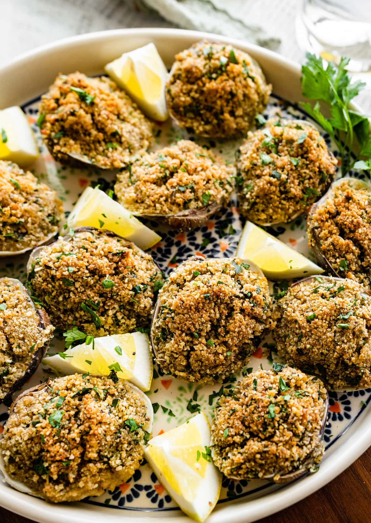 Best Italian Baked Stuffed Clams on a plate with lemon wedges and parsley.