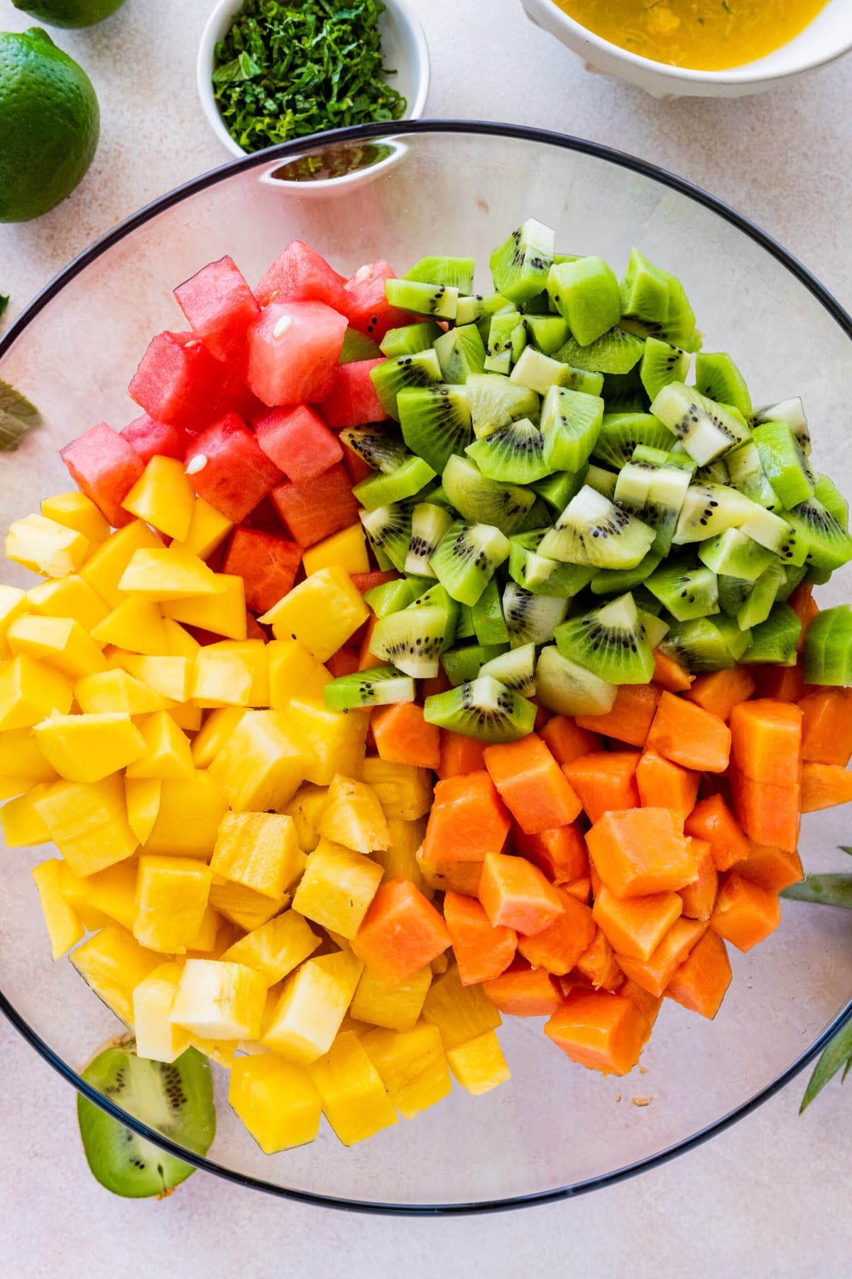 How to make Best and Easy Mexican Fruit Salad- adding all the fruit to a large glass bowl.