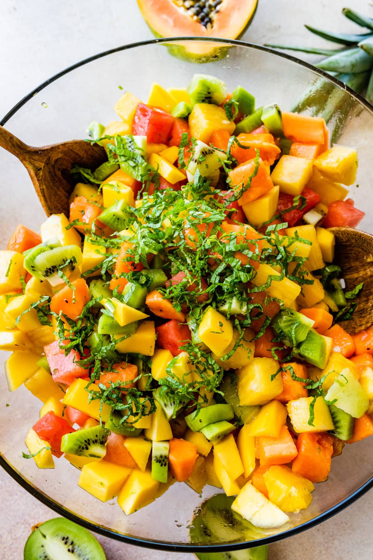 How to make Best and Easy Mexican Fruit Salad- adding all the fruit to a large glass bowl. Adding the dressing. add the mint and toss to combine.