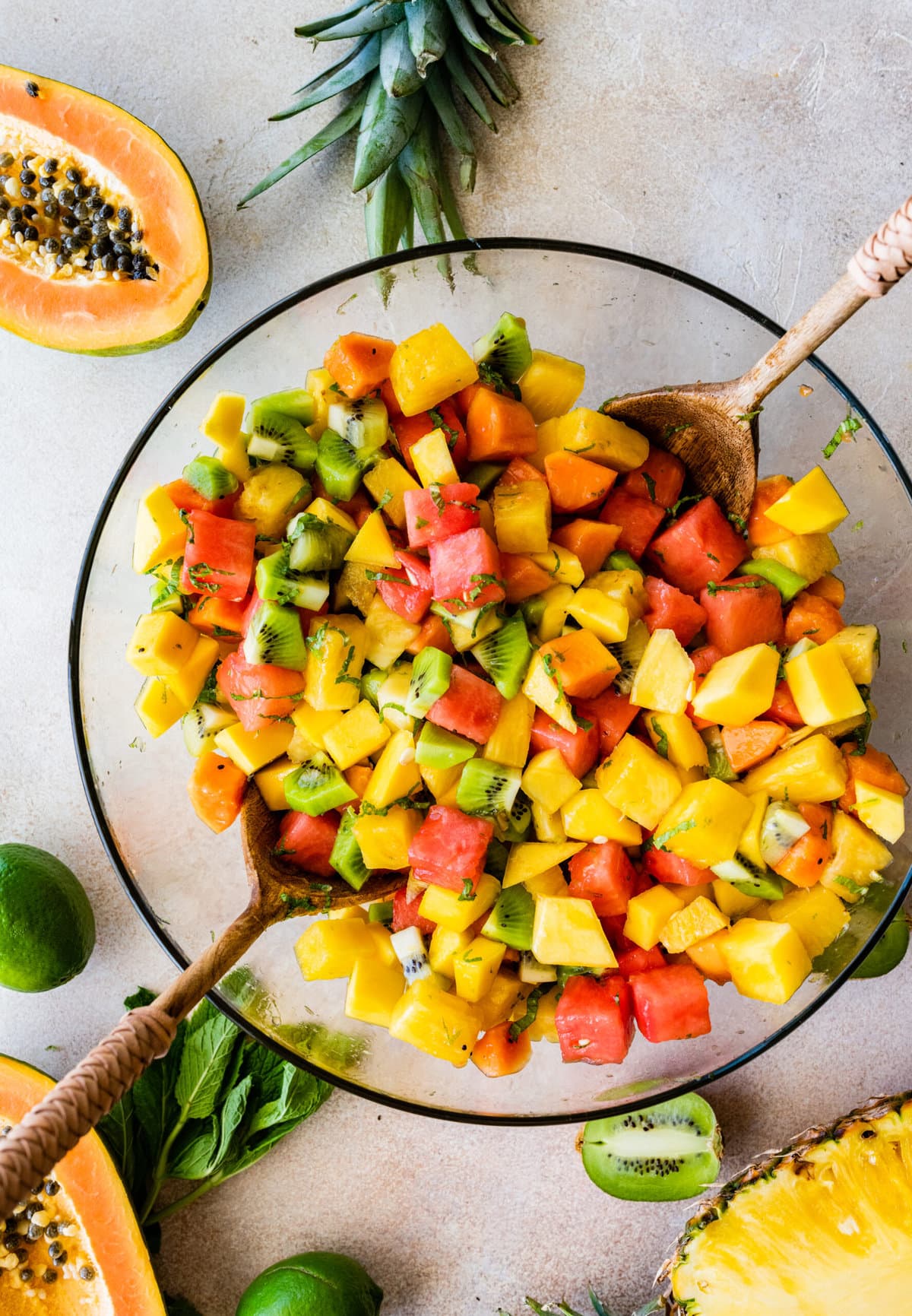 How to make Best and Easy Mexican Fruit Salad- adding all the fruit to a large glass bowl. Adding the dressing and toss to combine.