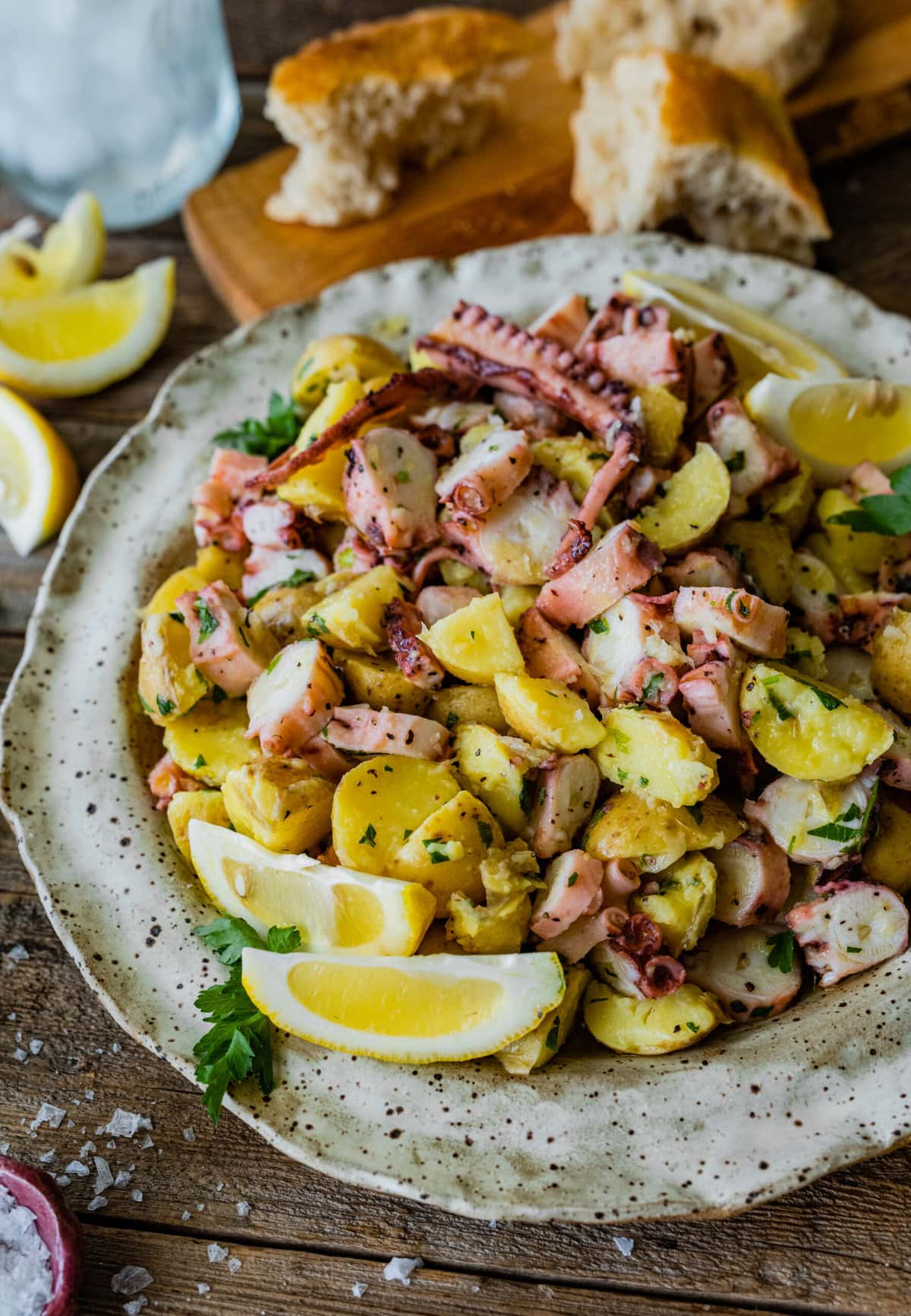 Italian Octopus Salad Recipe with Potatoes (Insalata Di Polpo) in a plate with a fork. Side of lemon and bread.