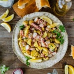 Italian Octopus Salad Recipe with Potatoes (Insalata Di Polpo) in a plate with a fork. Side of lemon and bread.