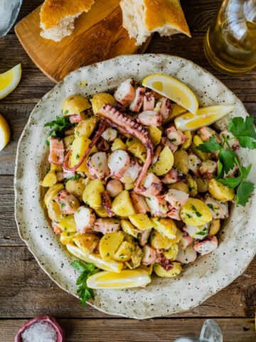 Italian Octopus Salad Recipe with Potatoes (Insalata Di Polpo) in a plate with a fork. Side of lemon and bread.