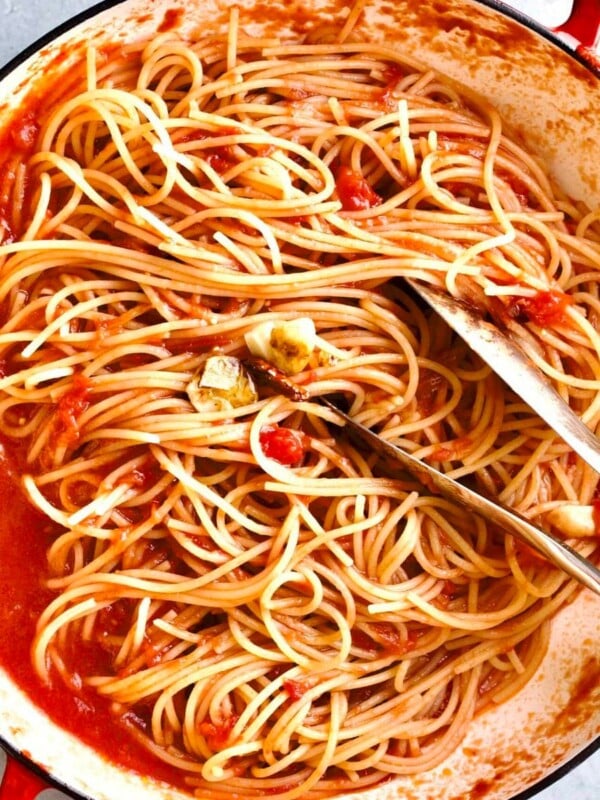 Spaghetti with tomato sauce in a pan with tongs
