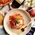 Quick Tomato Paste Pasta Sauce Recipe with Spaghetti on a plate. All the products and ingredients surround the plate of spaghetti.
