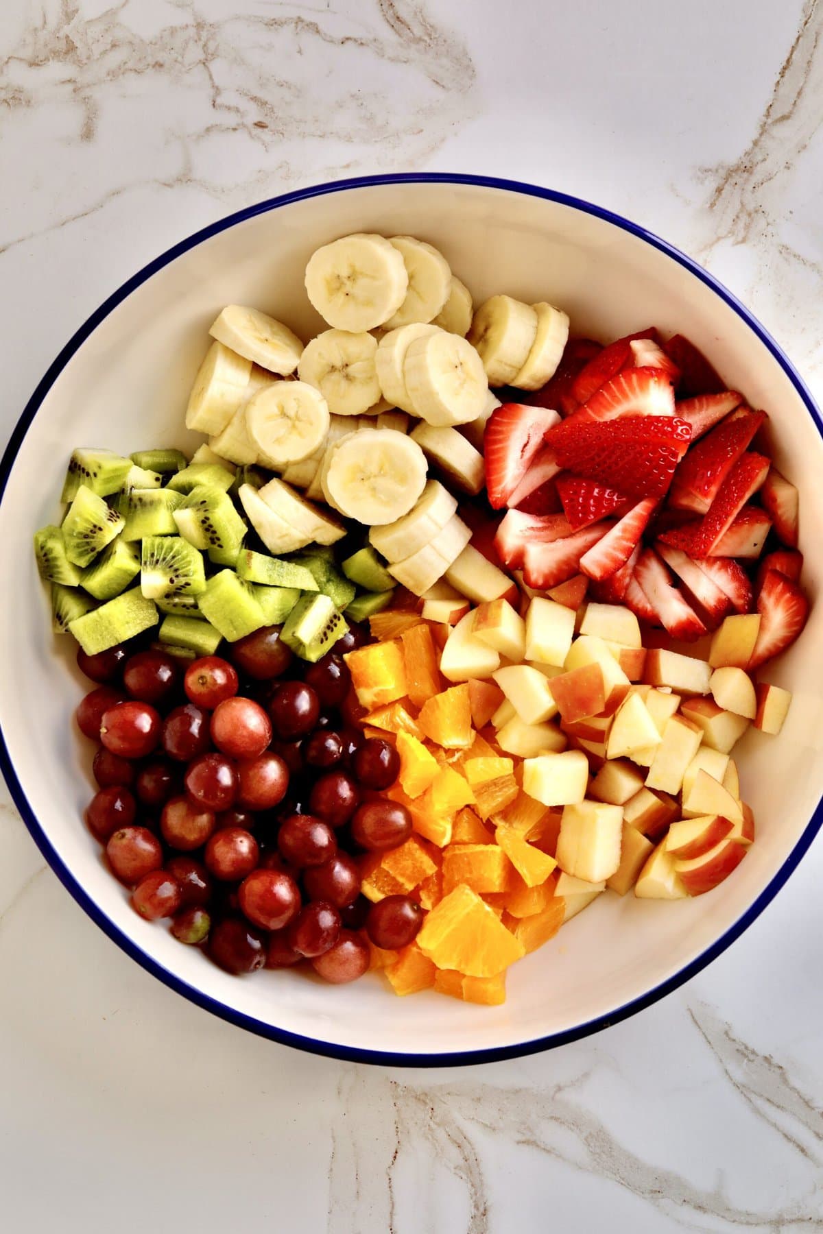 How to make Italian fruit salad recipe- chopping all the fruit and adding it to the bowl.