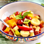 Spoon in a bowl of Italian fruit salad.