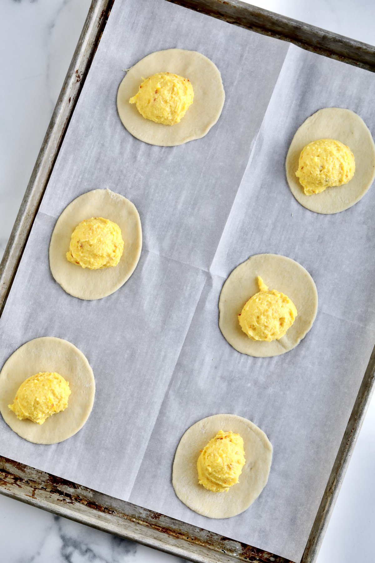 How to make Sardinian Pardulas Recipe- place pastry dough circles on a cookie sheet and fill with the ricotta filling.