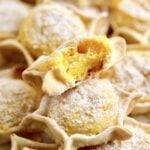 Best Sardinian Pardulas Recipe (Ricotta Cakes)- bite taken out of one pardulas. soft interior. other pardulas in the background.