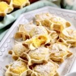 Best Sardinian Pardulas Recipe (Ricotta Cakes)- bite taken out of one pardulas. soft interior. other pardulas in the background.