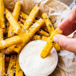 Crispy polenta fries with herbs dipped in the aioli. Close up photo.