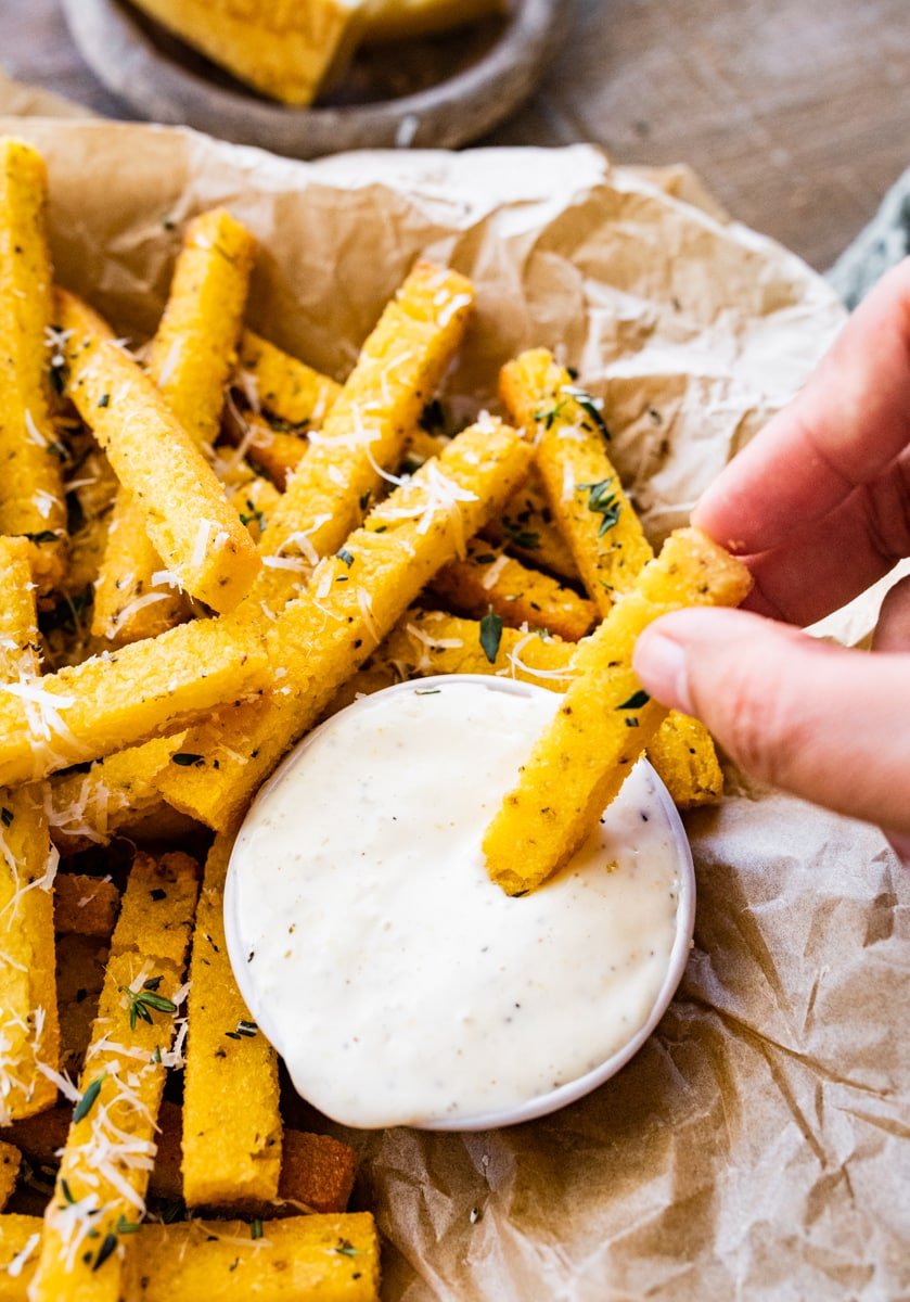Crispy polenta fries with herbs dipped in the aioli. Close up photo. 