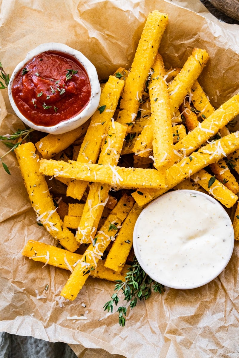 Crispy polenta fries with herbs dipped in the aioli. Close up photo.