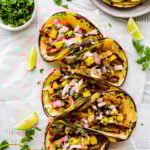 Homemade Tacos Al Pastor Recipe (Tacos De Trompo)- assembled tacos on a plate ready to eat. Limes and parsley on the side.