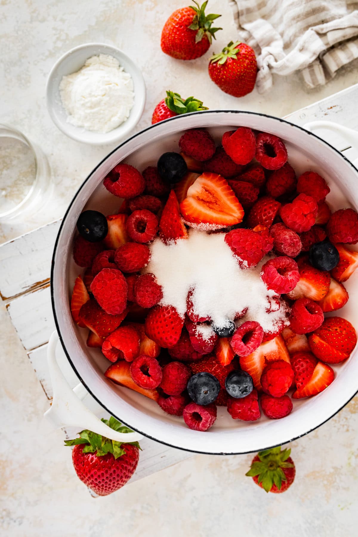 Making the berry puree. Adding the sugar and berries in a pot.