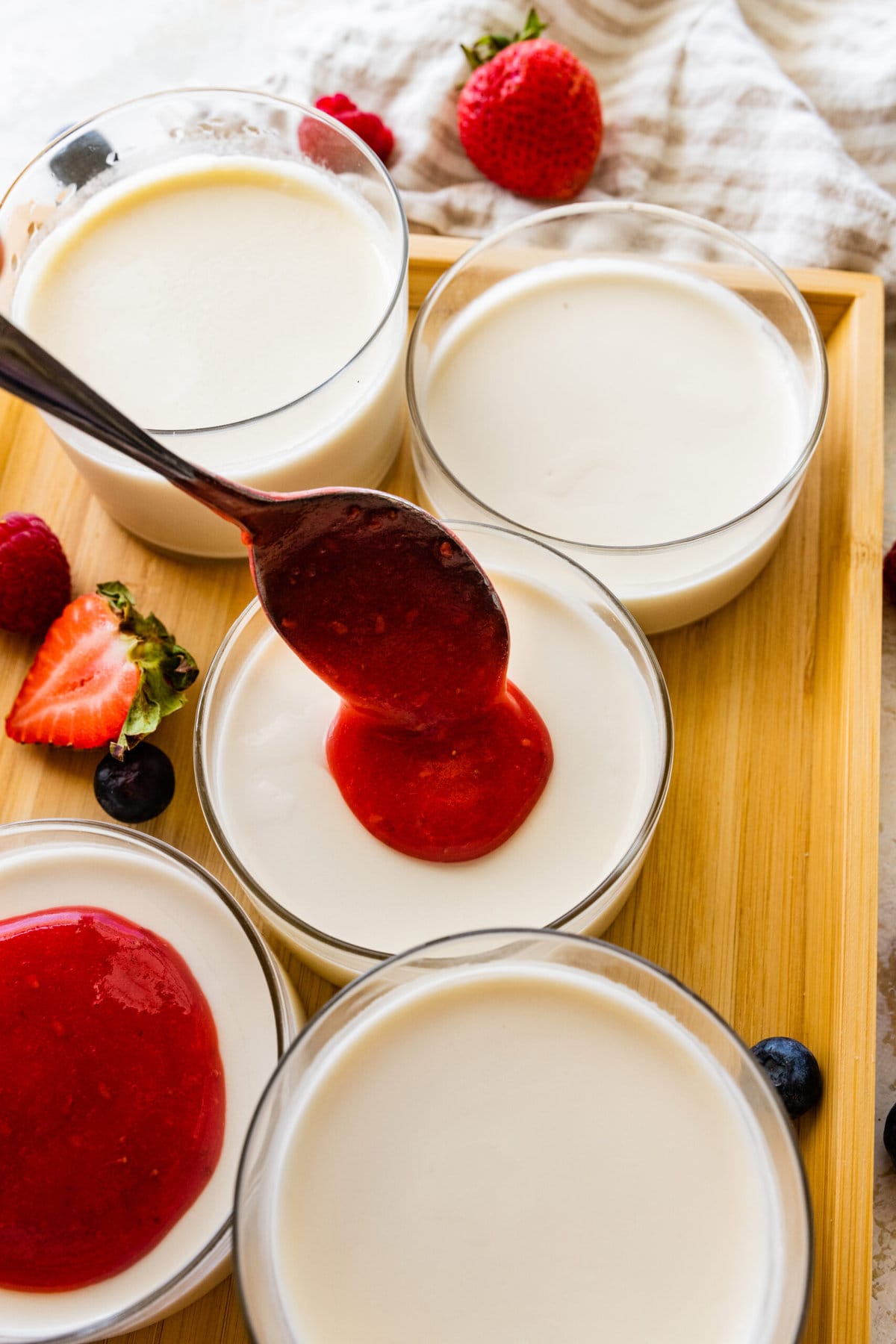 How to Make Classic Italian Panna Cotta Recipe Easy- adding berry sauce on top of the chilled panna cotta.