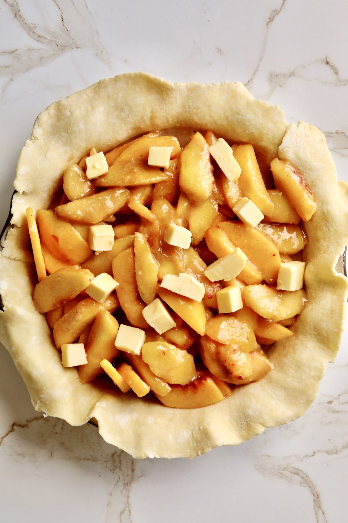 How to make fresh peach pie recipe step-by-step: adding prepared filling and dotting with butter.