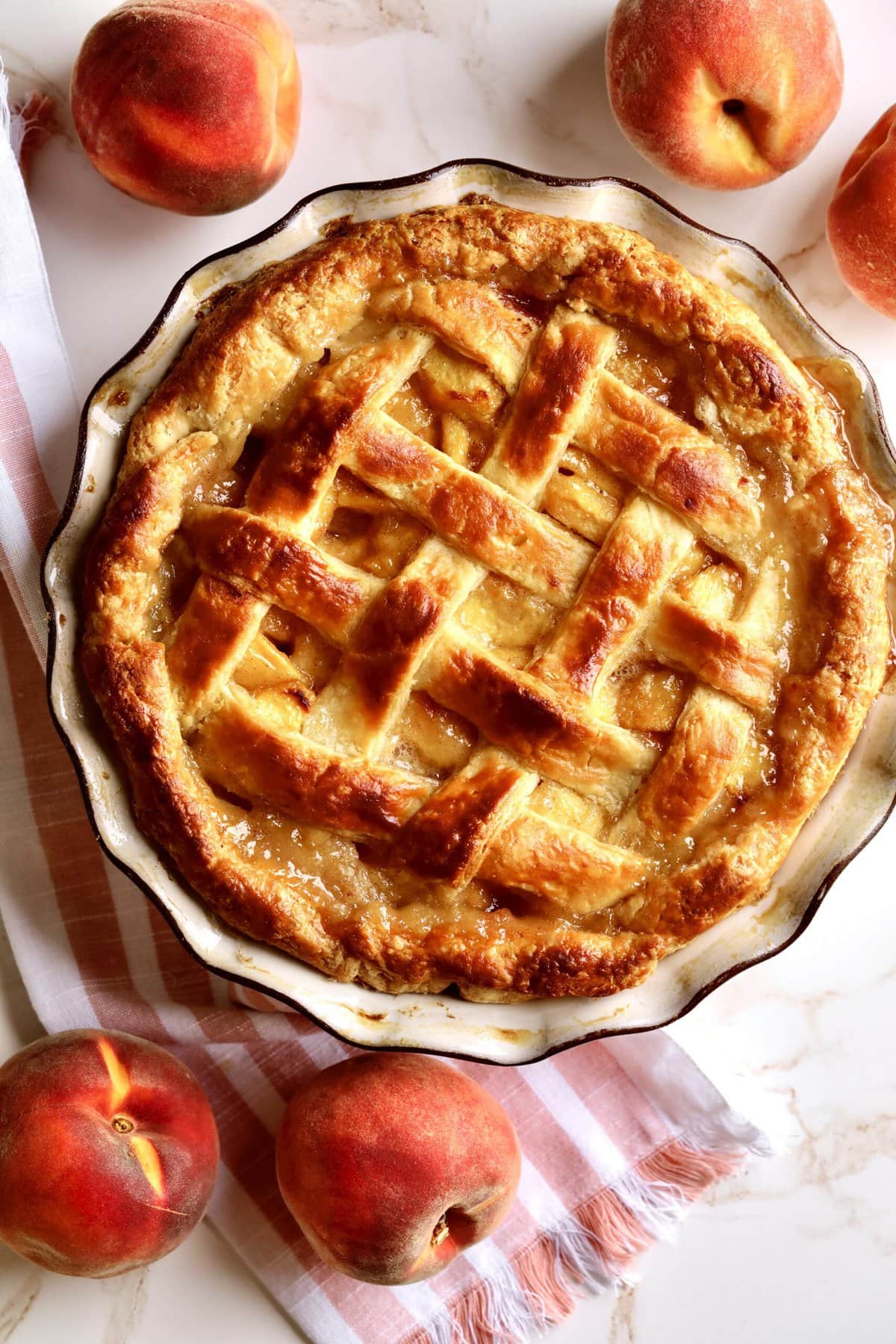 Fresh peach pie with lattice top in a pie pan.