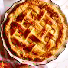 Fresh peach pie with lattice top in a pie pan.