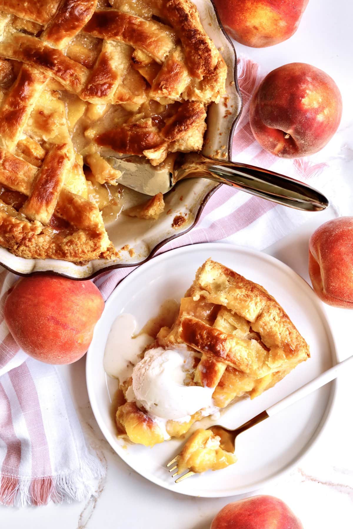 slice of the perfect peach pie on a plate with a fork. Ice cream on top of the slice melting slightly. downward shot also showing the rest of the pie in the pie plate.