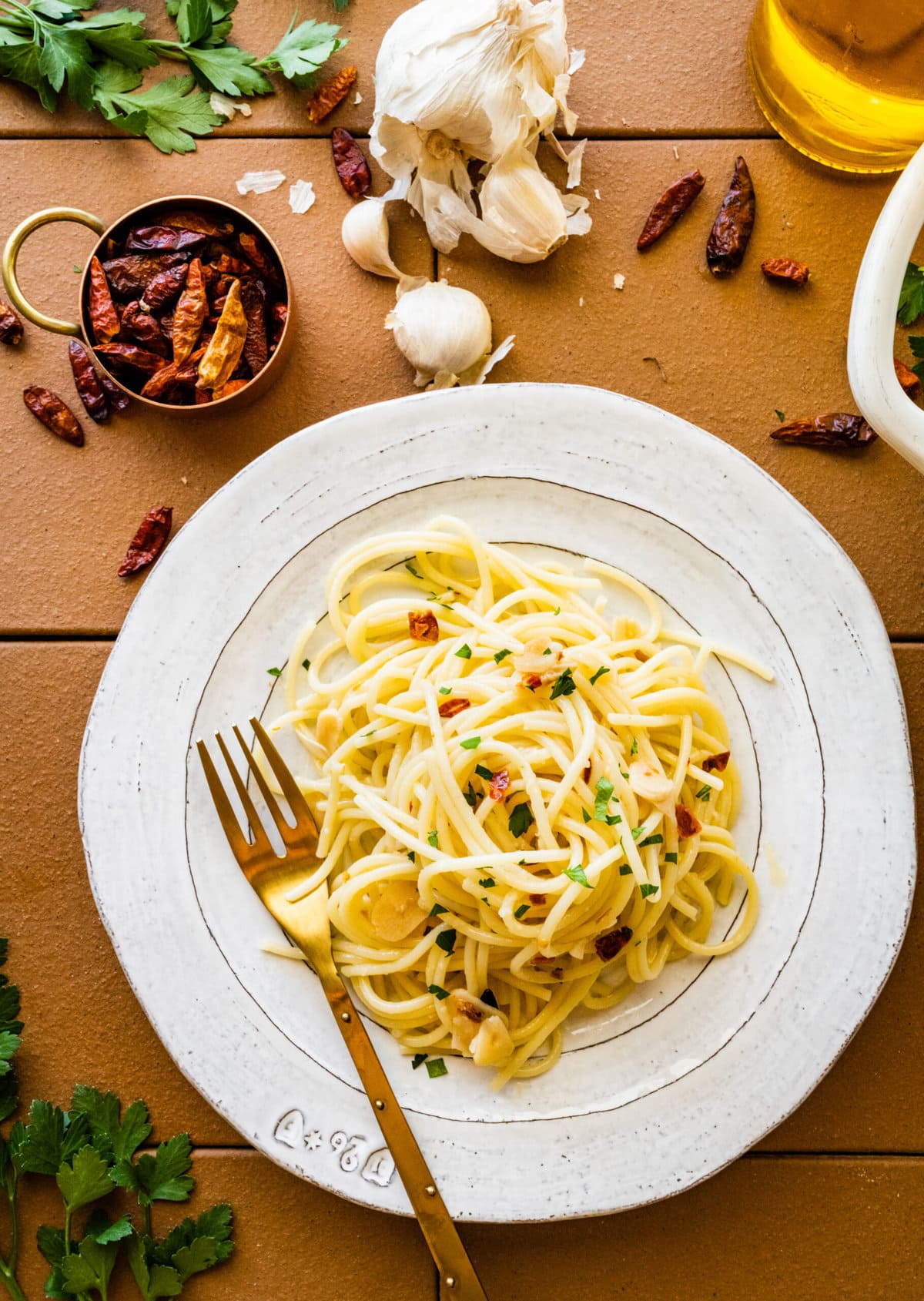 Aglio e olio pasta recipe on a plate ready to eat. garlic and dried red peppers on background