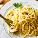 Aglio e olio pasta recipe on a plate ready to eat. Fork twirling the pasta.
