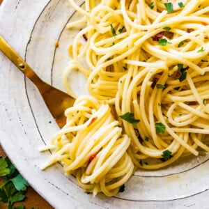 Aglio e olio pasta recipe on a plate ready to eat. Fork twirling the pasta.