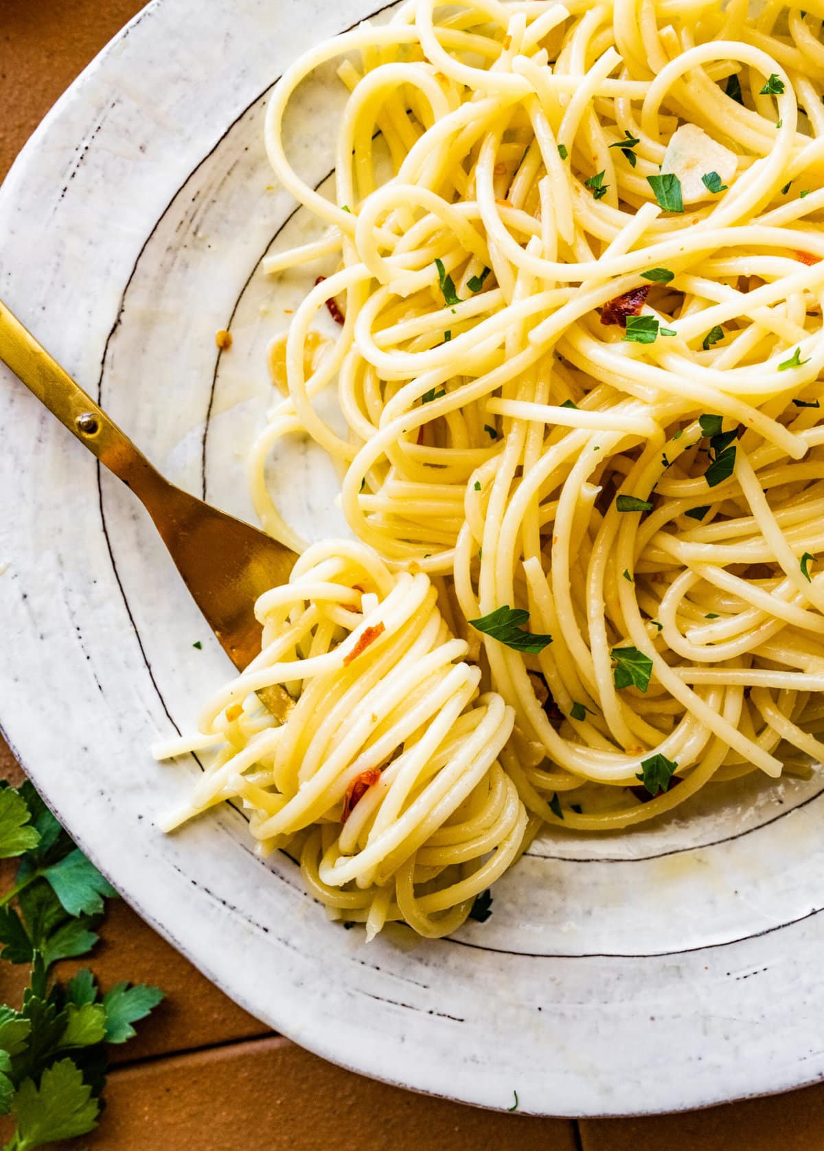Aglio e olio pasta recipe on a plate ready to eat. Fork twirling the pasta.