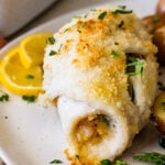 baked stuffed flounder on a plate with lemon wedges.