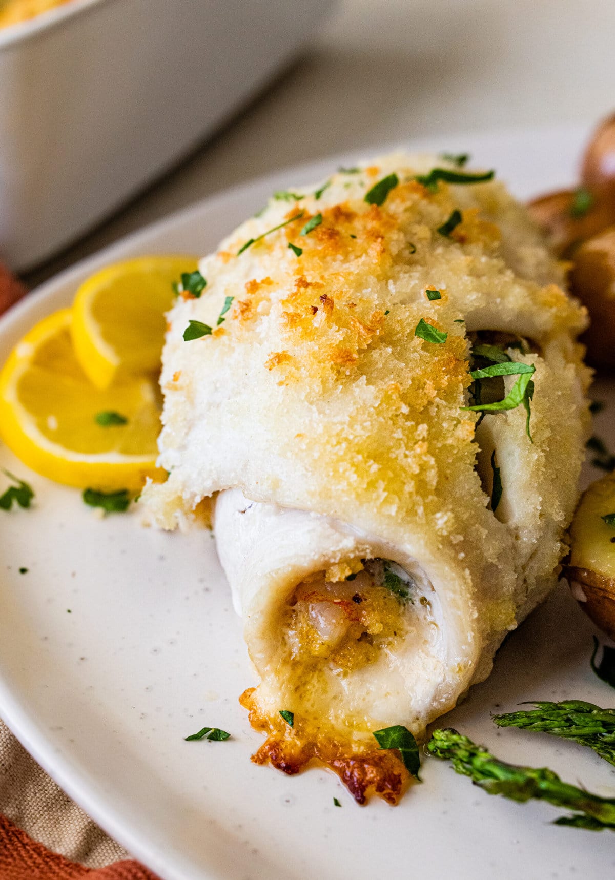 baked stuffed flounder on a plate with lemon wedges.
