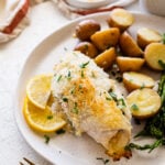 baked stuffed flounder on a plate with lemon wedges. potatoes and asparagus on a plate.