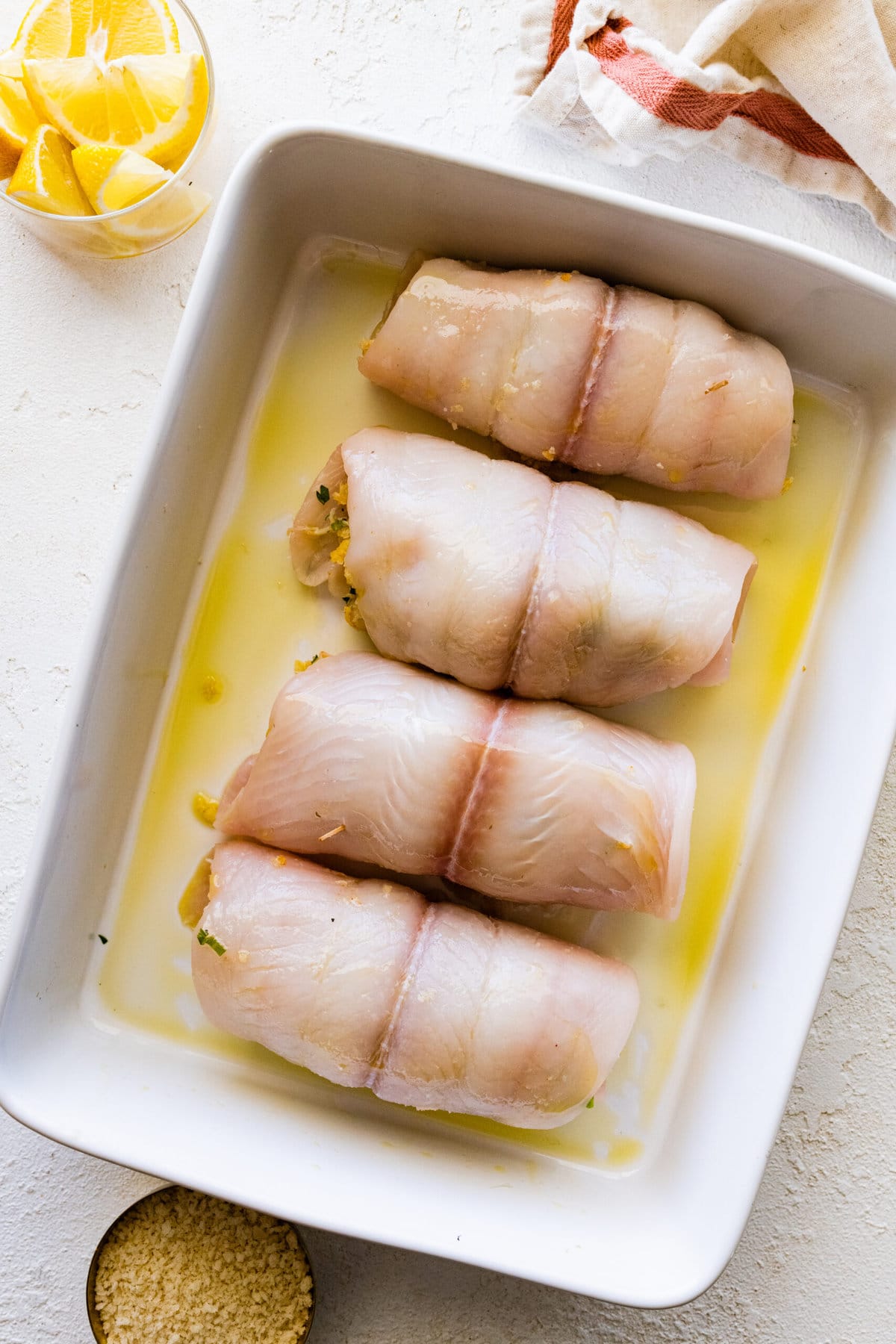 How to make stuffed flounder recipe- placing fish in a serving dish with olive oil.