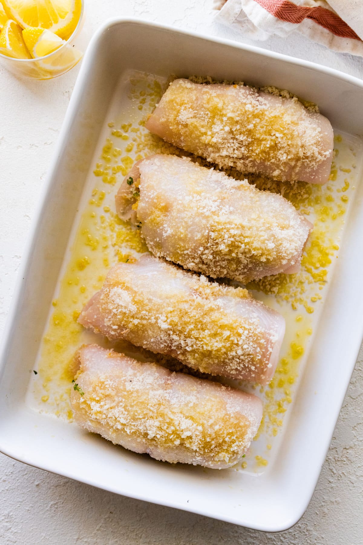 How to make stuffed flounder recipe- adding the topping and lemon olive oil on top of the fish before baking. Getting ready to put in the oven.