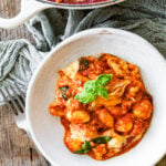gnocchi alla sorrentina in a bowl ready to eat with pan of gnocchi in the background.