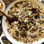 creamy mushroom risotto in a wide pan with wooden spoon.