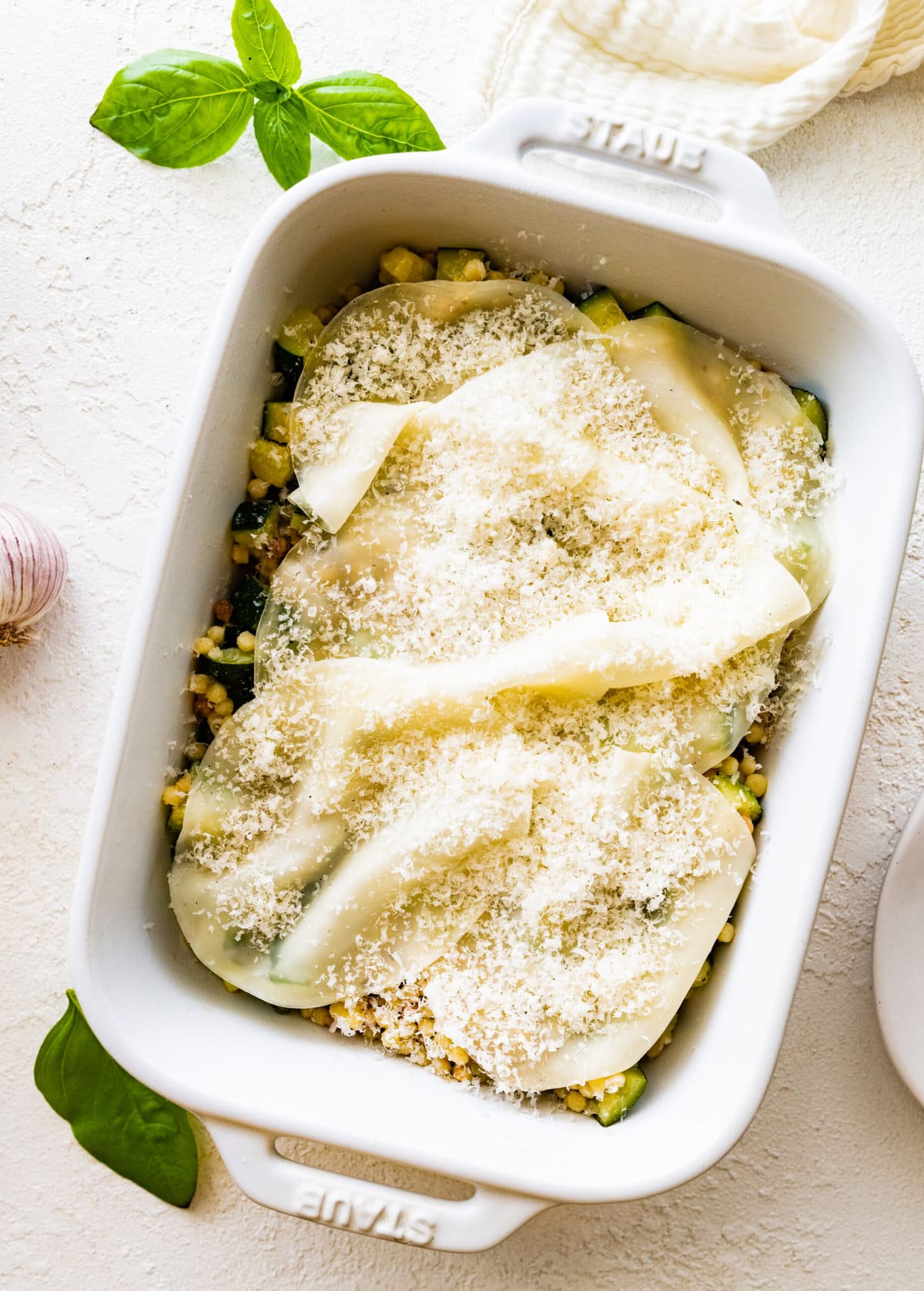 Step by step instructions Fregola Sarda Pasta Recipe with Zucchini and Cheese- place finished pasta and zucchini mixture in oven safe pan. Layer with cheese.
