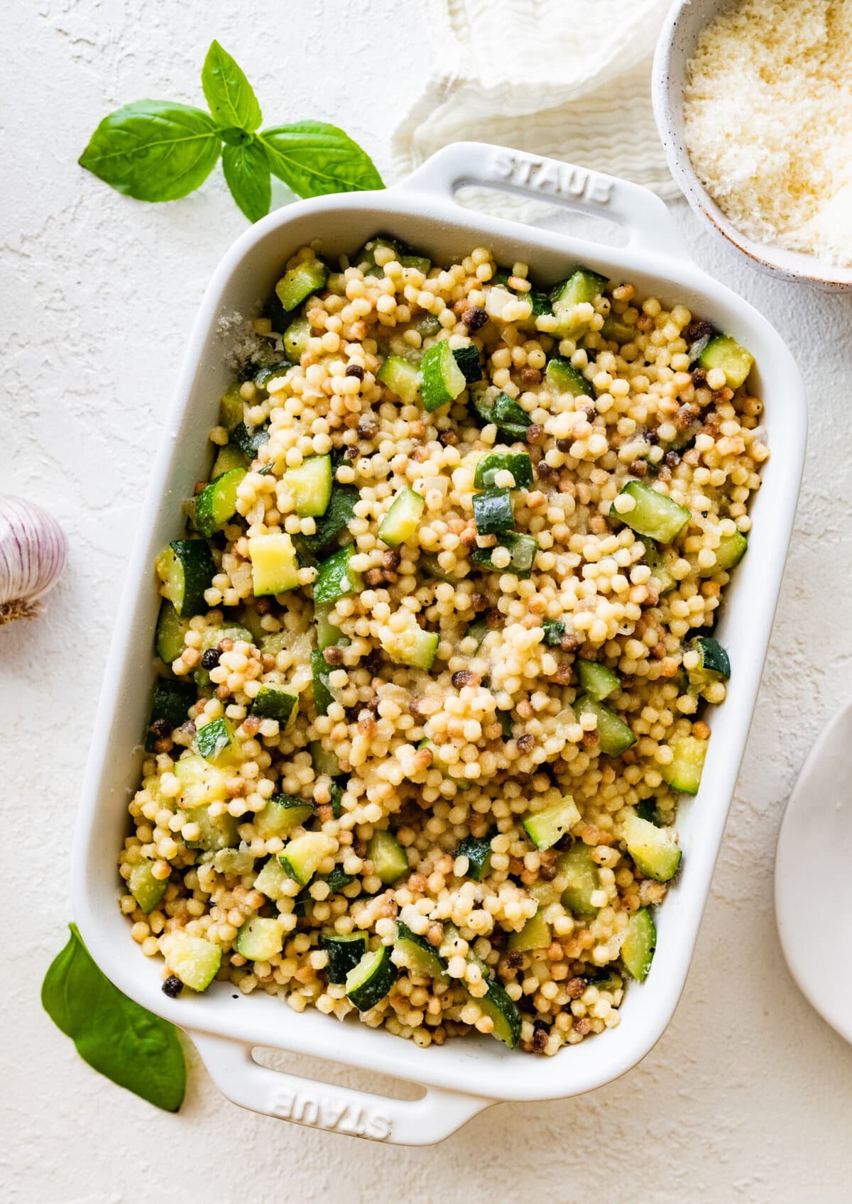 Step by step instructions Fregola Sarda Pasta Recipe with Zucchini and Cheese- place finished pasta and zucchini mixture in oven safe pan. Layer with cheese. Add more of the pasta mixture.