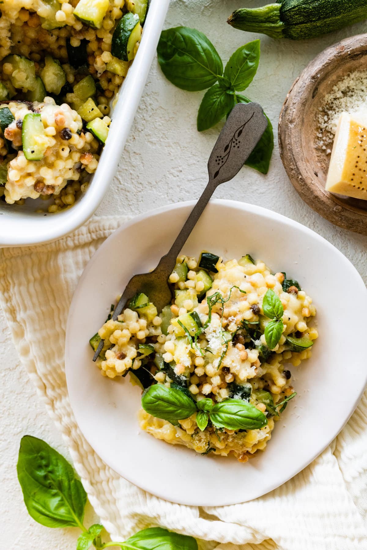 finished Fregola Sarda Pasta Recipe with Zucchini and Cheese in pan. Up close shot with wood spoon taking out a portion.