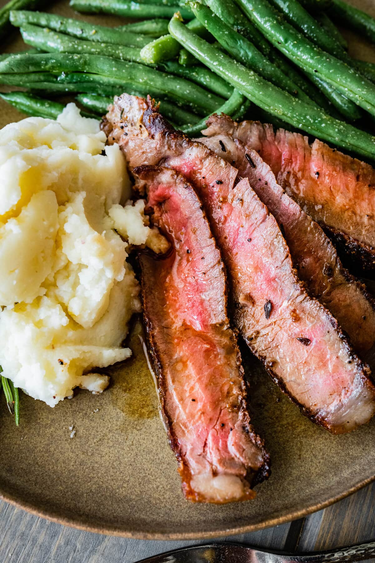 T-Bone Steak on a plate with mashed potatoes and green beans. Close up.