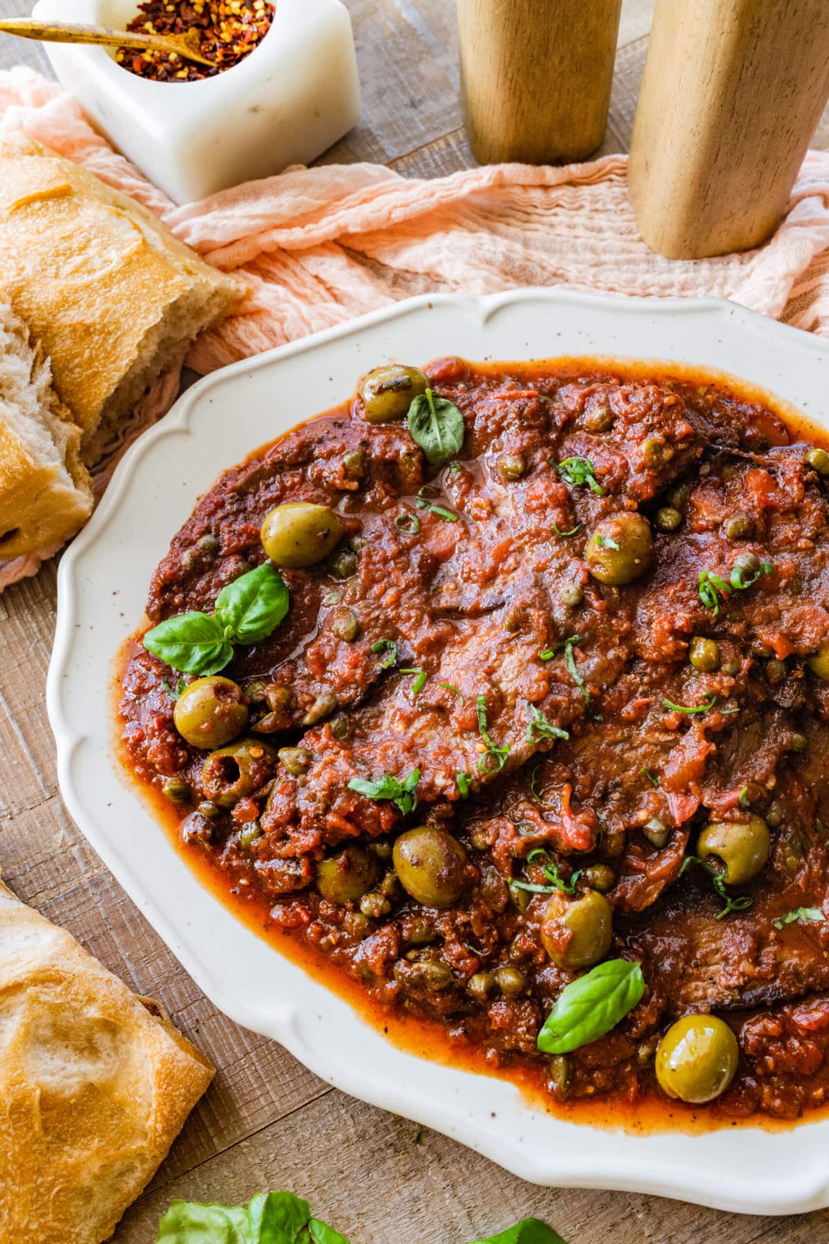 platted steak pizzaiola recipe in a white dish with bread on the side to serve.