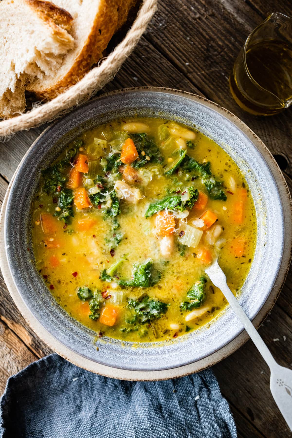 finished white bean soup in a bowl with parmigiano cheese on top on a wood background. 