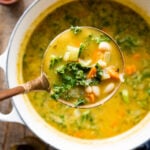 finished Tuscan white bean soup with a ladle lifting up a portion.