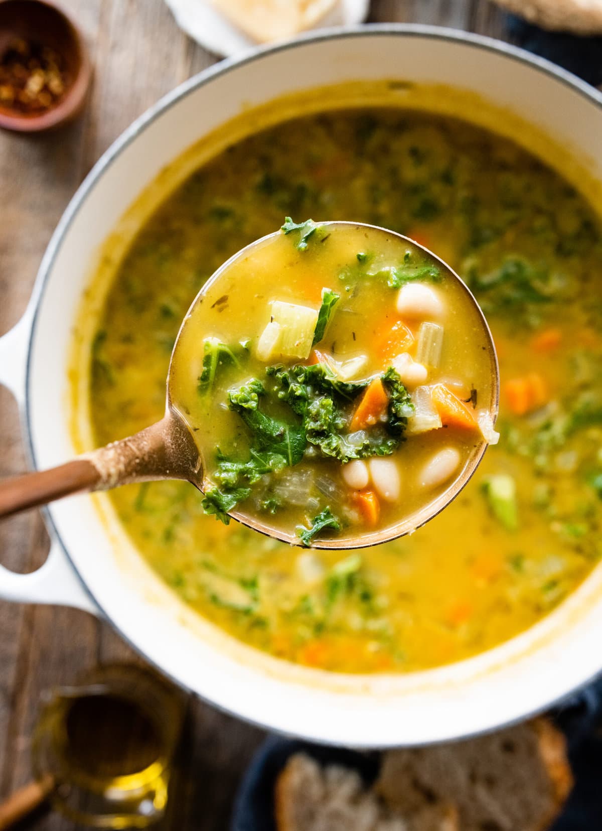 finished Tuscan white bean soup with a ladle lifting up a portion.