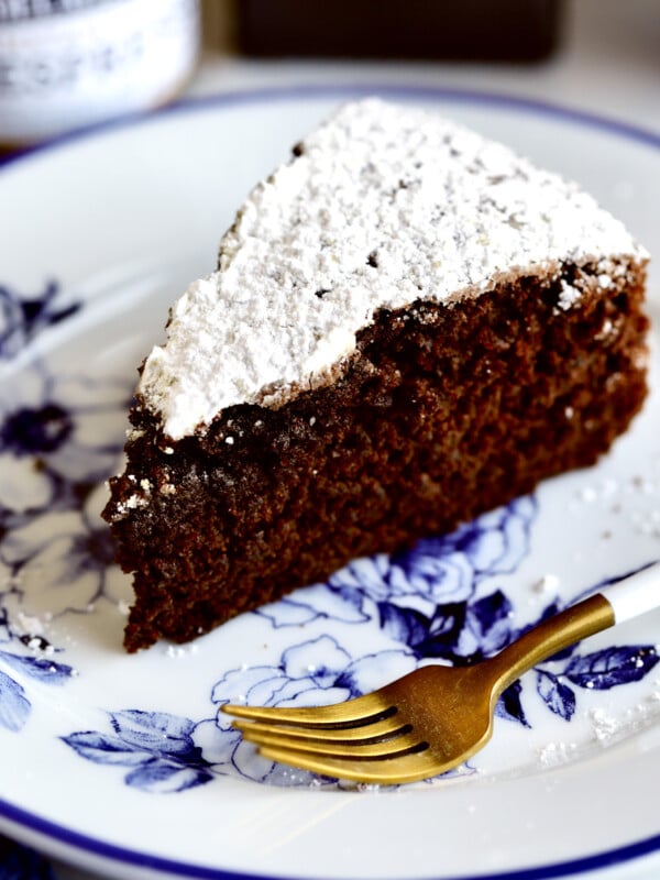 Slice of chocolate olive oil cake on a blue and white floral plate with a fork.