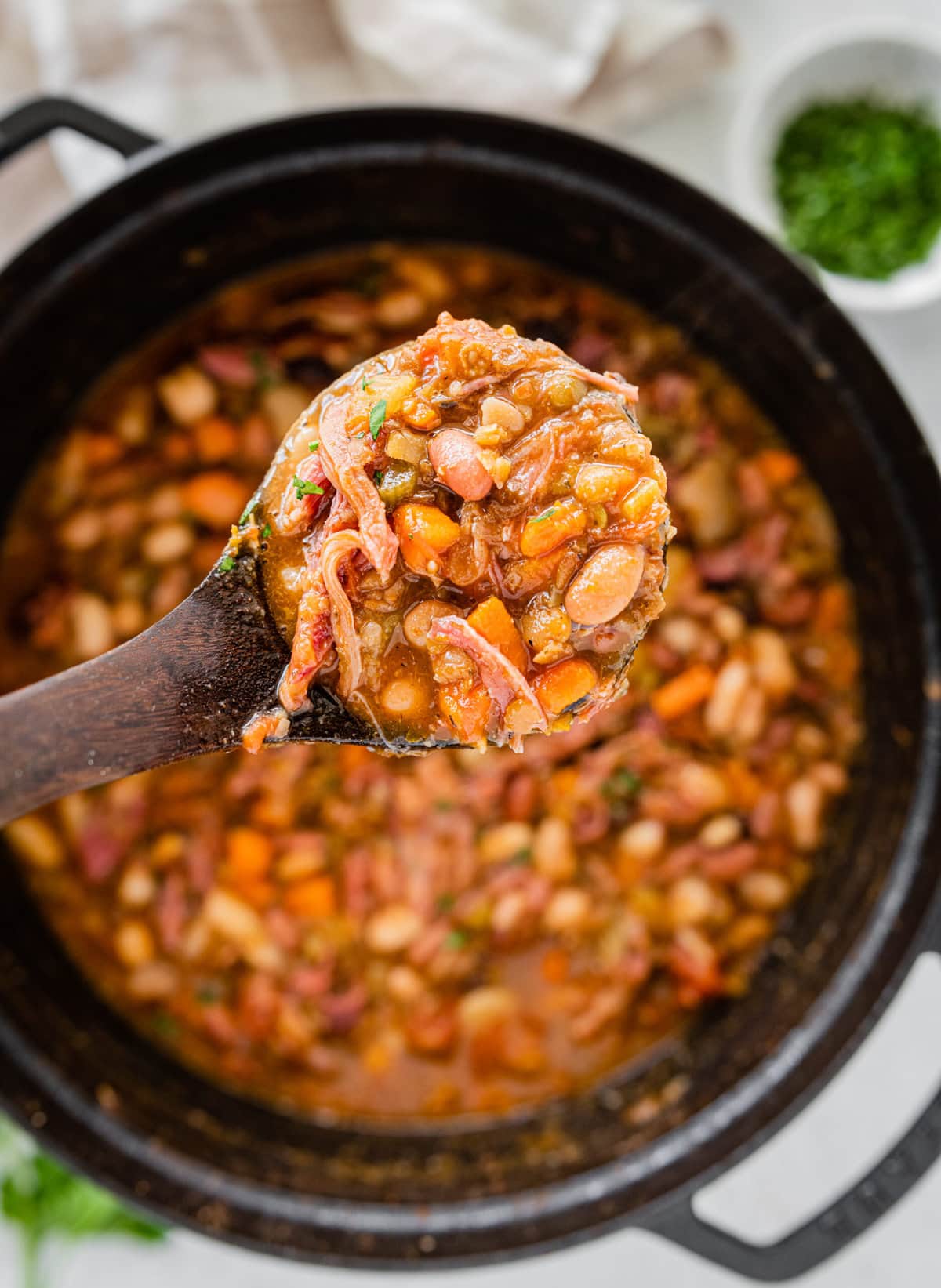 wooden ladle showing the cooked 15 bean soup with ham.