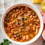 15 bean soup mix recipe in a white bowl with hands holding the bowl.