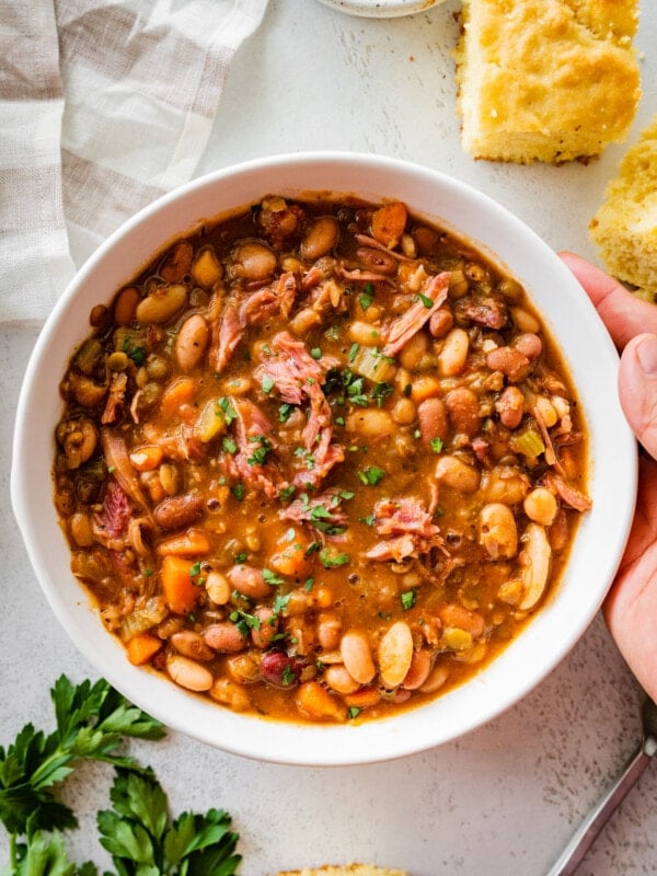 15 bean soup mix recipe in a white bowl with hands holding the bowl.