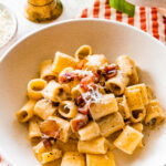 authentic pasta alla gricia on a plate with red and white checked napkin.