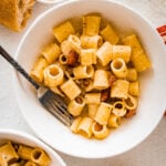 close up of pasta alla gricia in a bowl with a fork ready to eat.