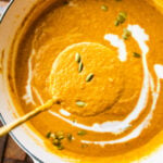 Ladle coming out of pot of soup showing the autumn squash soup.